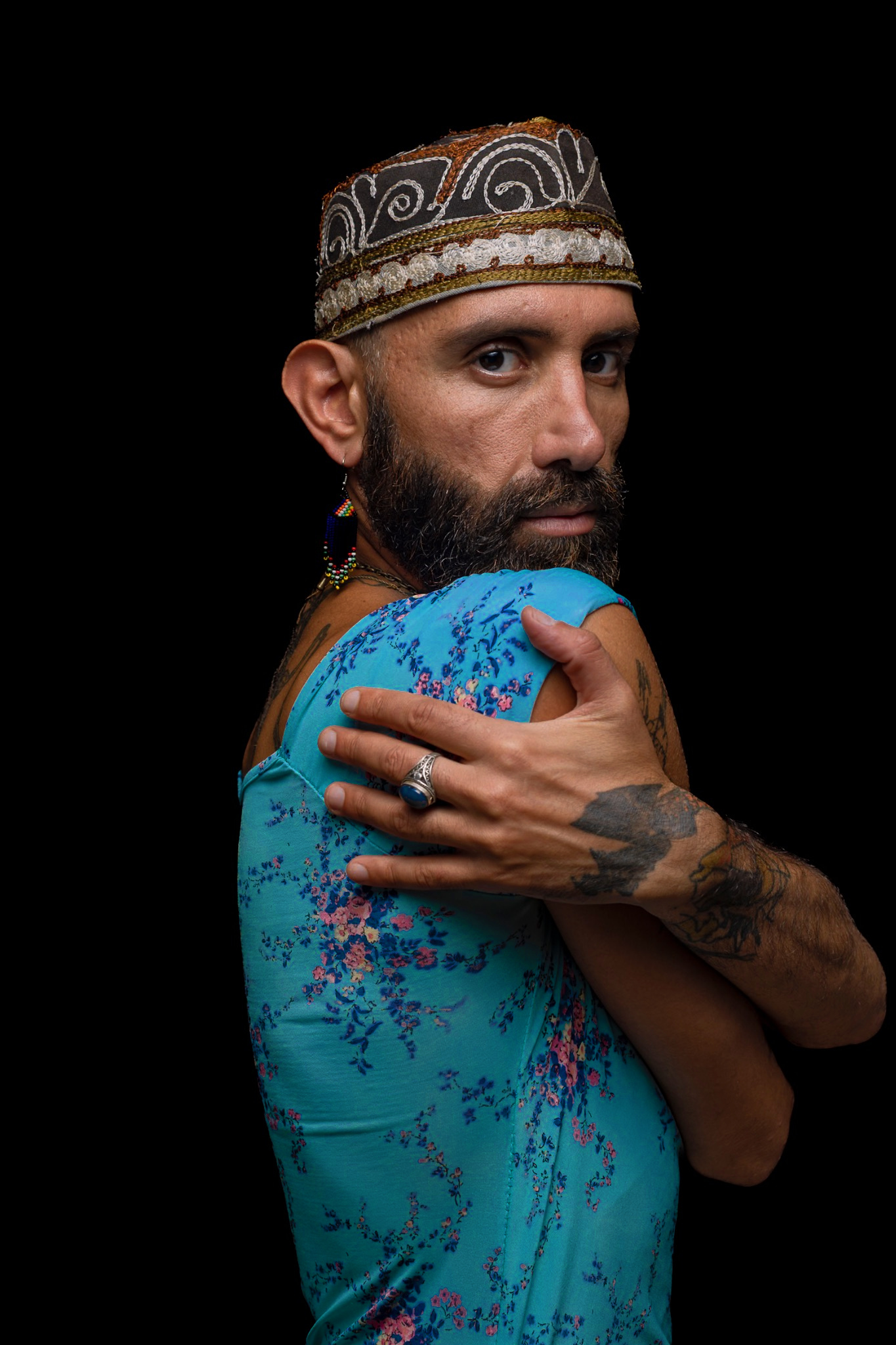 A sitter in an embroidered cap holds deep turquoise floral fabric around the shoulders.