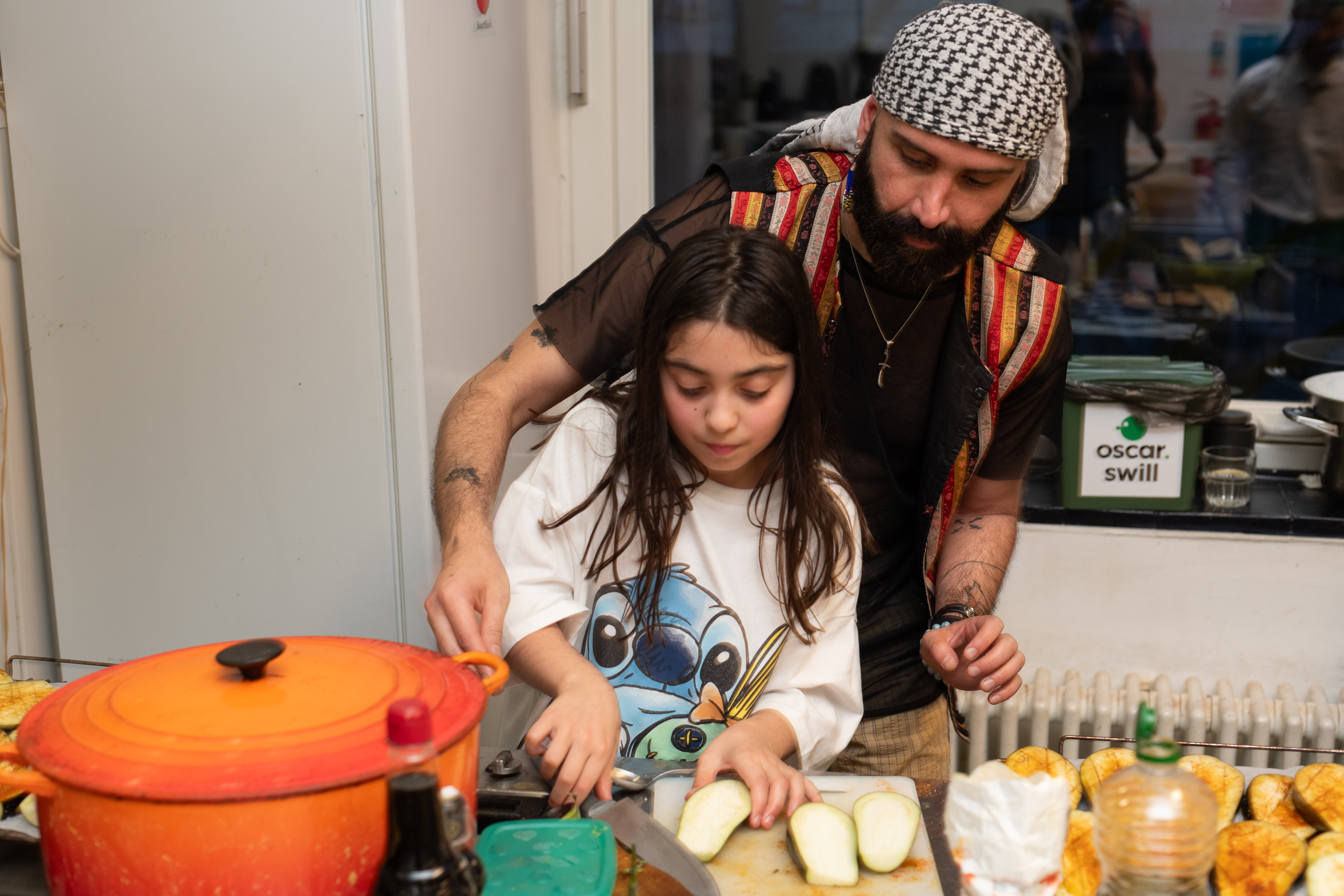 An adult and a child prepare vegetables together at a kitchen counter.