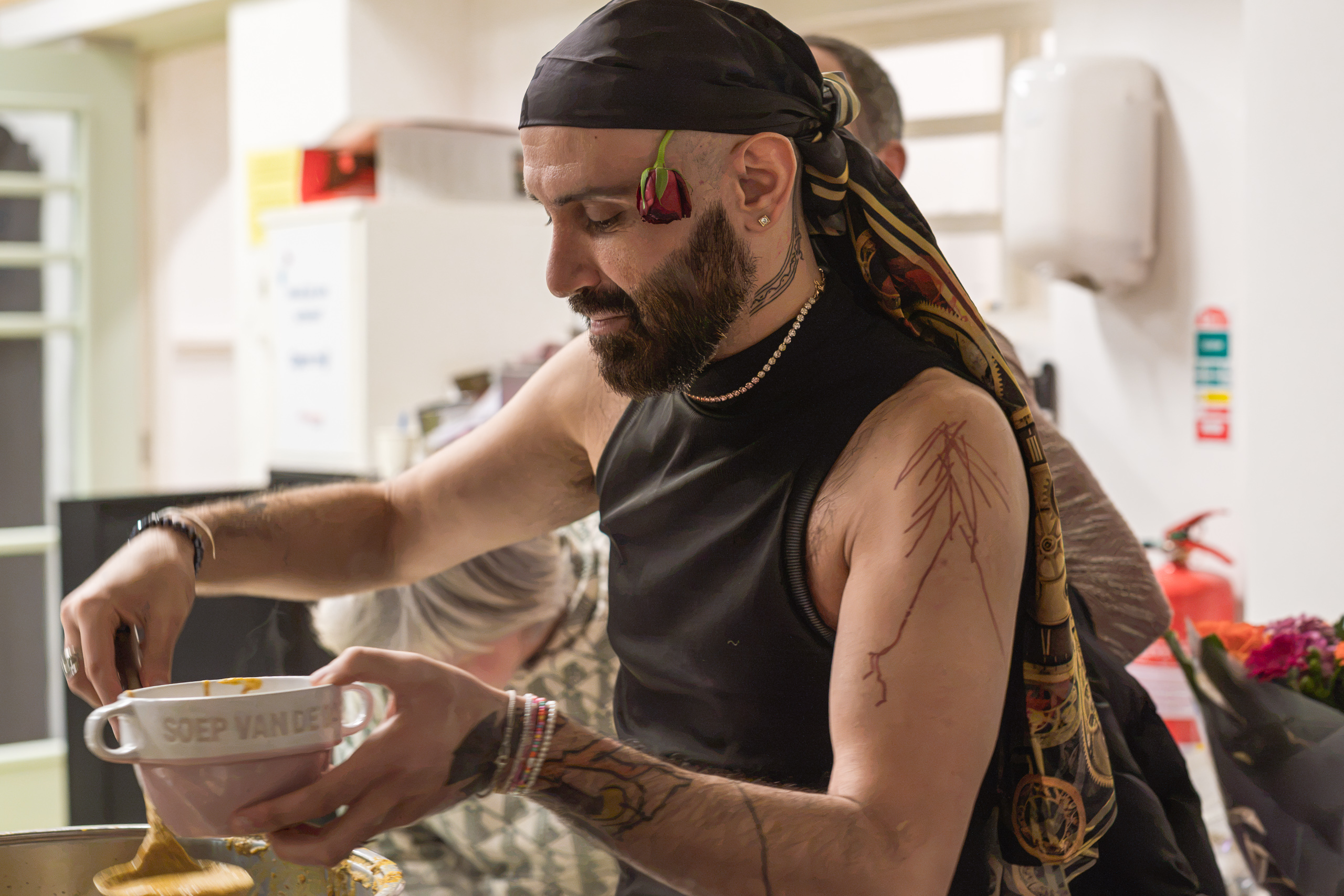 A person with a rose beside their face concentrates on a bowl while preparing food.