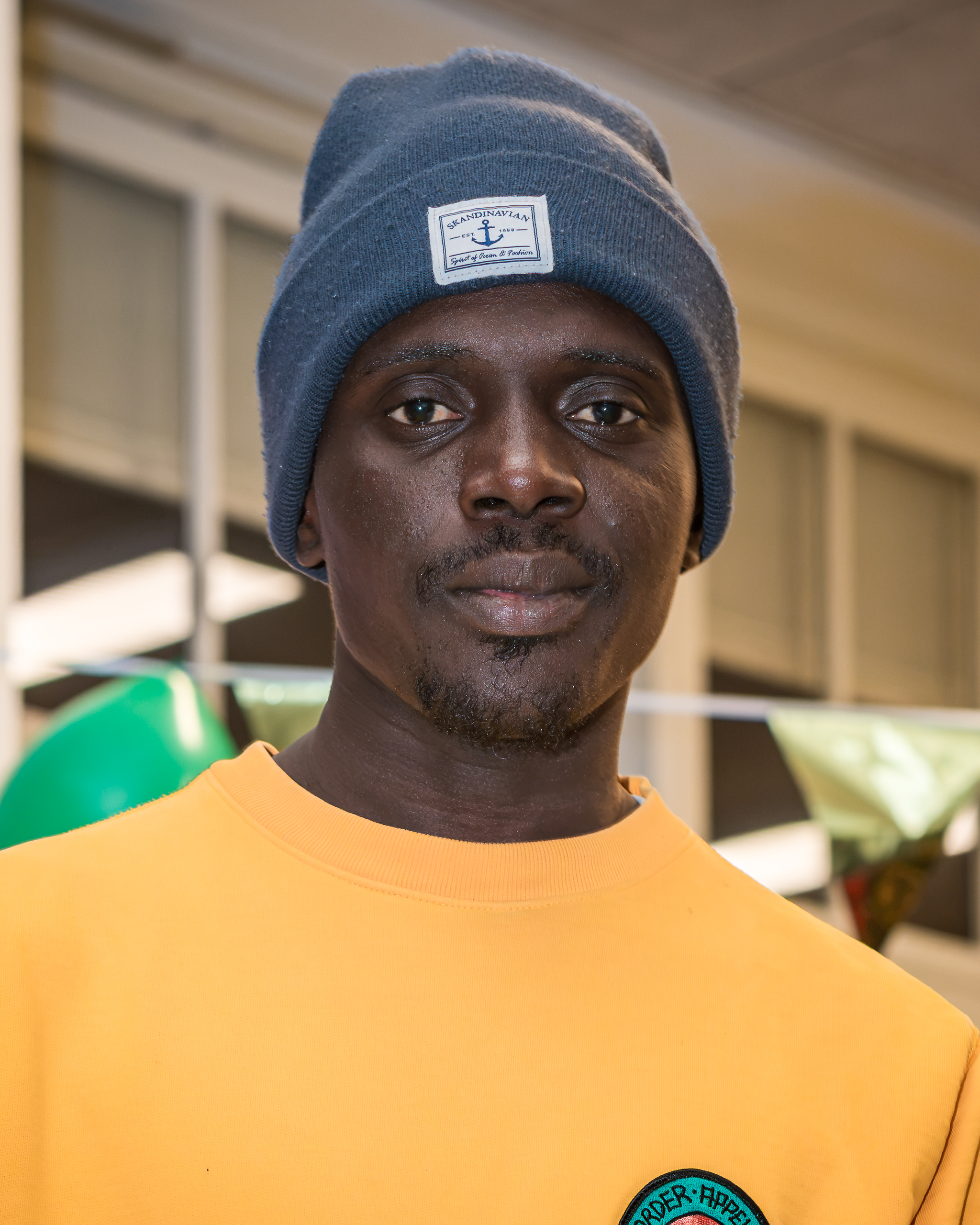 Direct portrait of a person in a yellow sweatshirt and blue beanie.