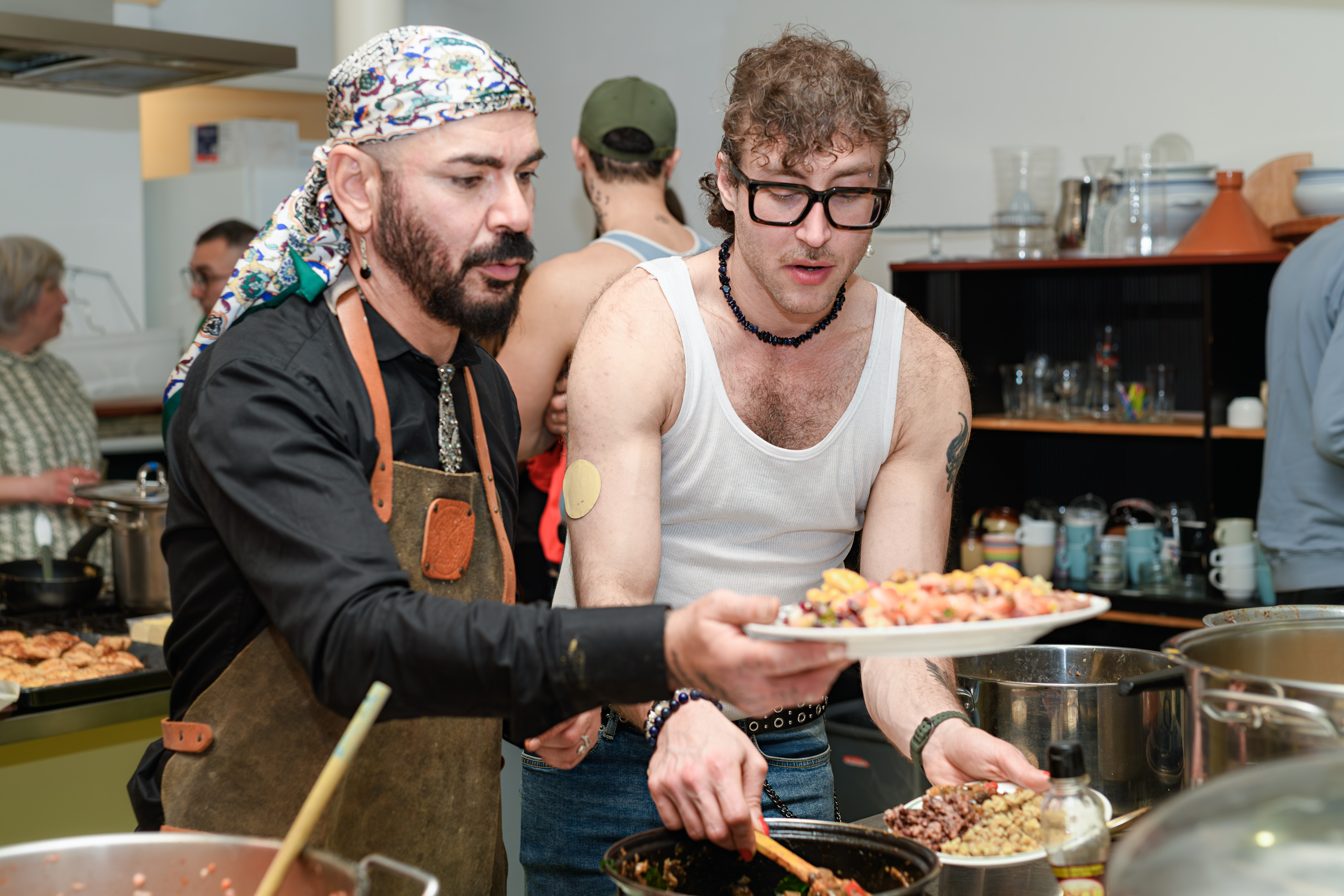 Two people serve food together, their arms crossing around a plate and ladle.