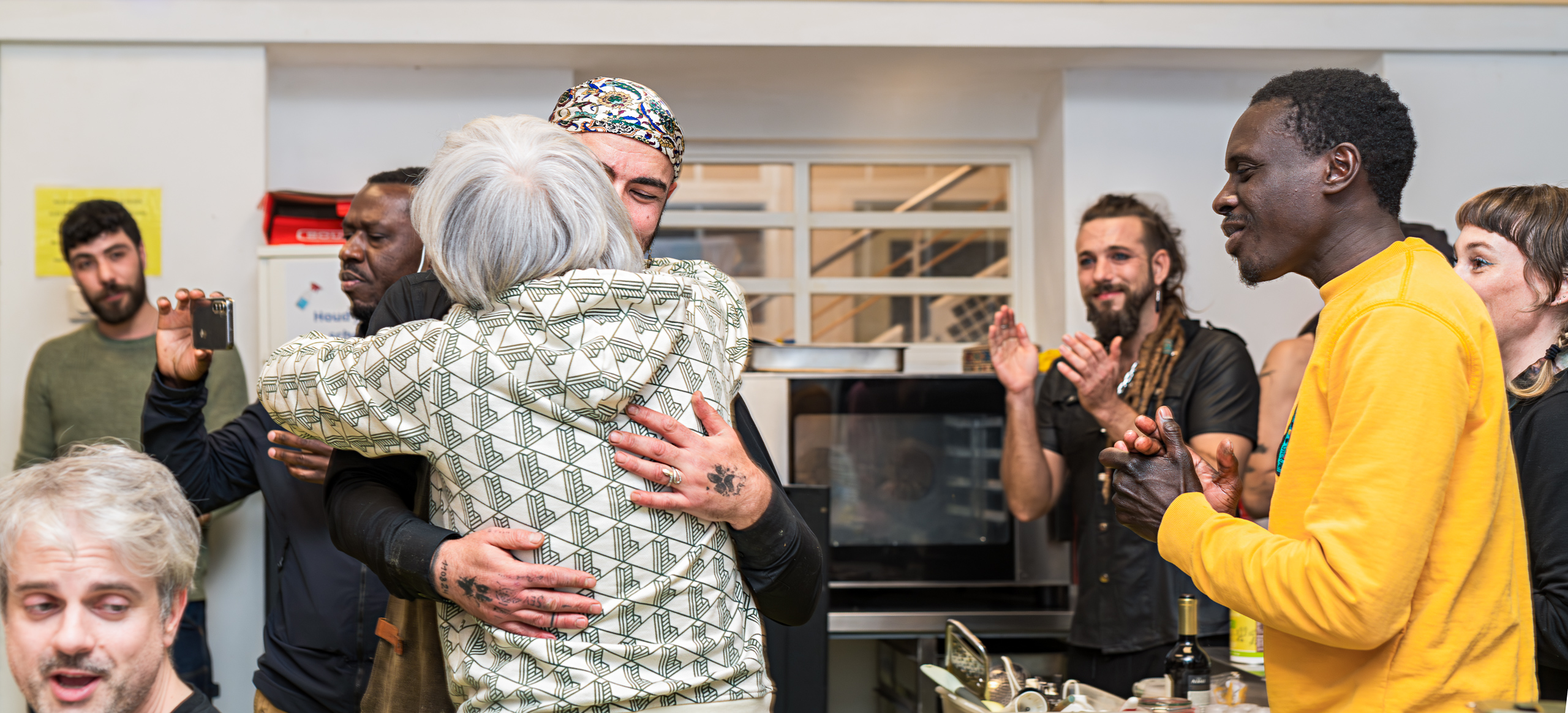 Two people embrace as those around them applaud.
