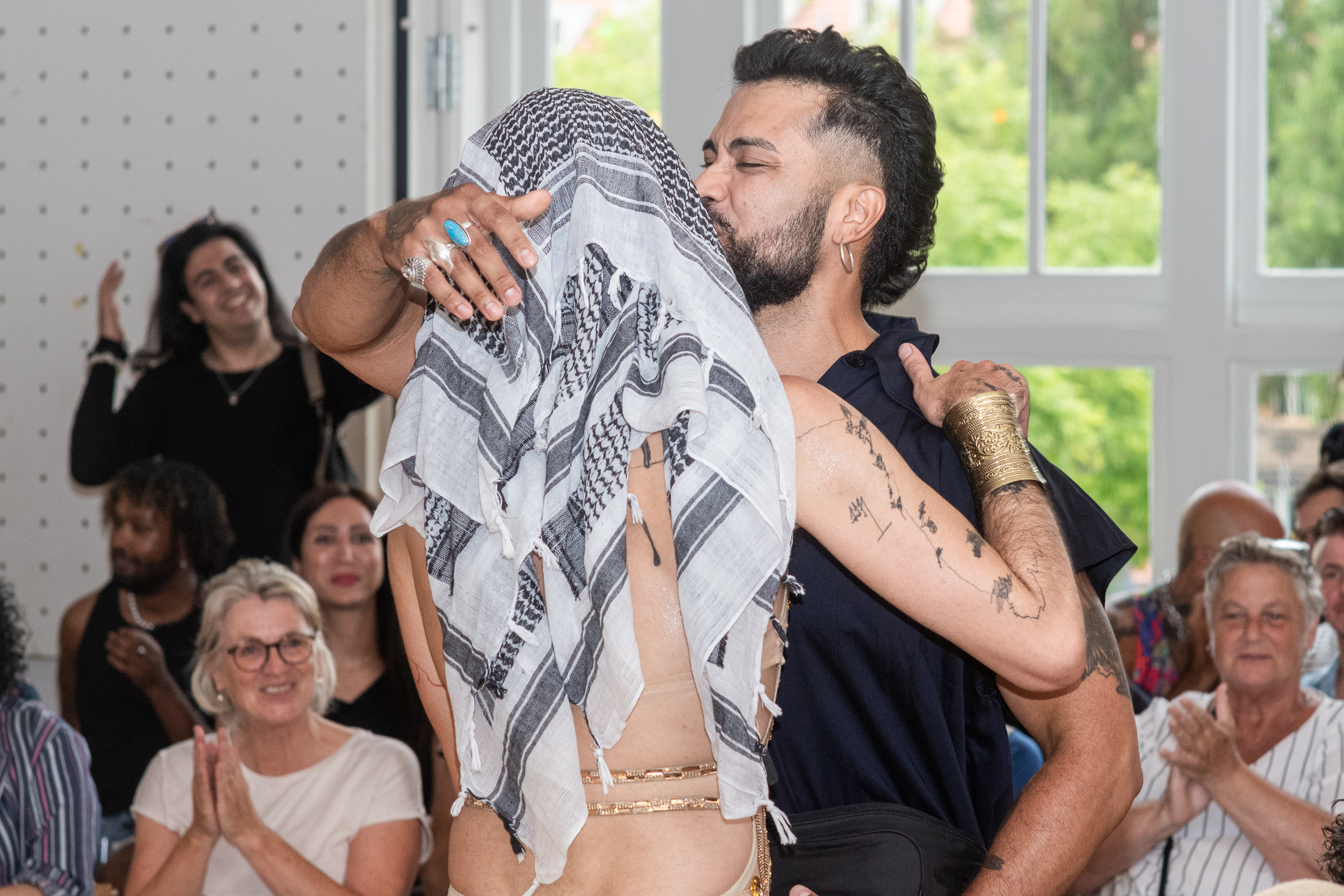 Two people embrace during a performance while the surrounding audience applauds.