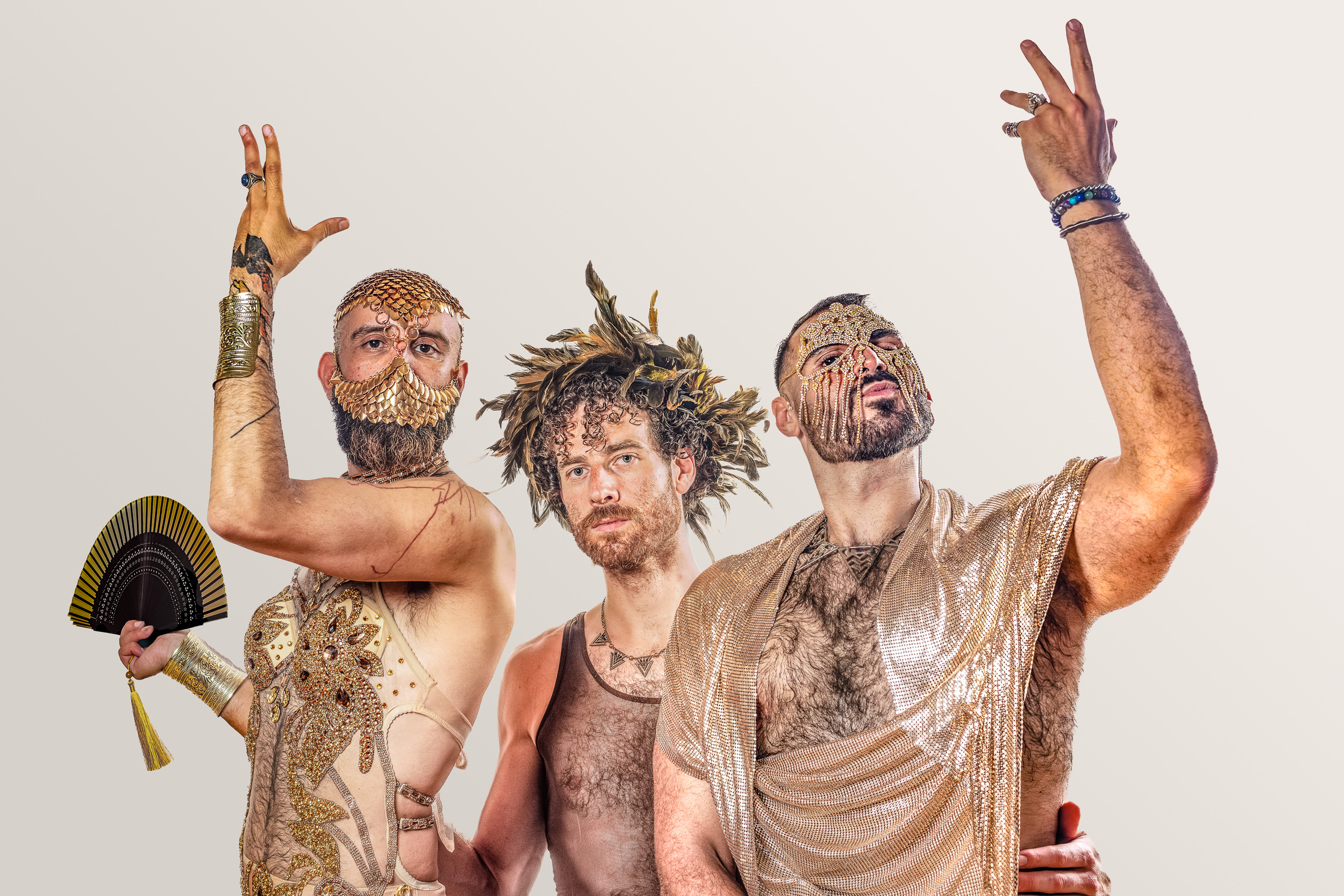 Three costumed figures pose together with gold adornments and raised arms.