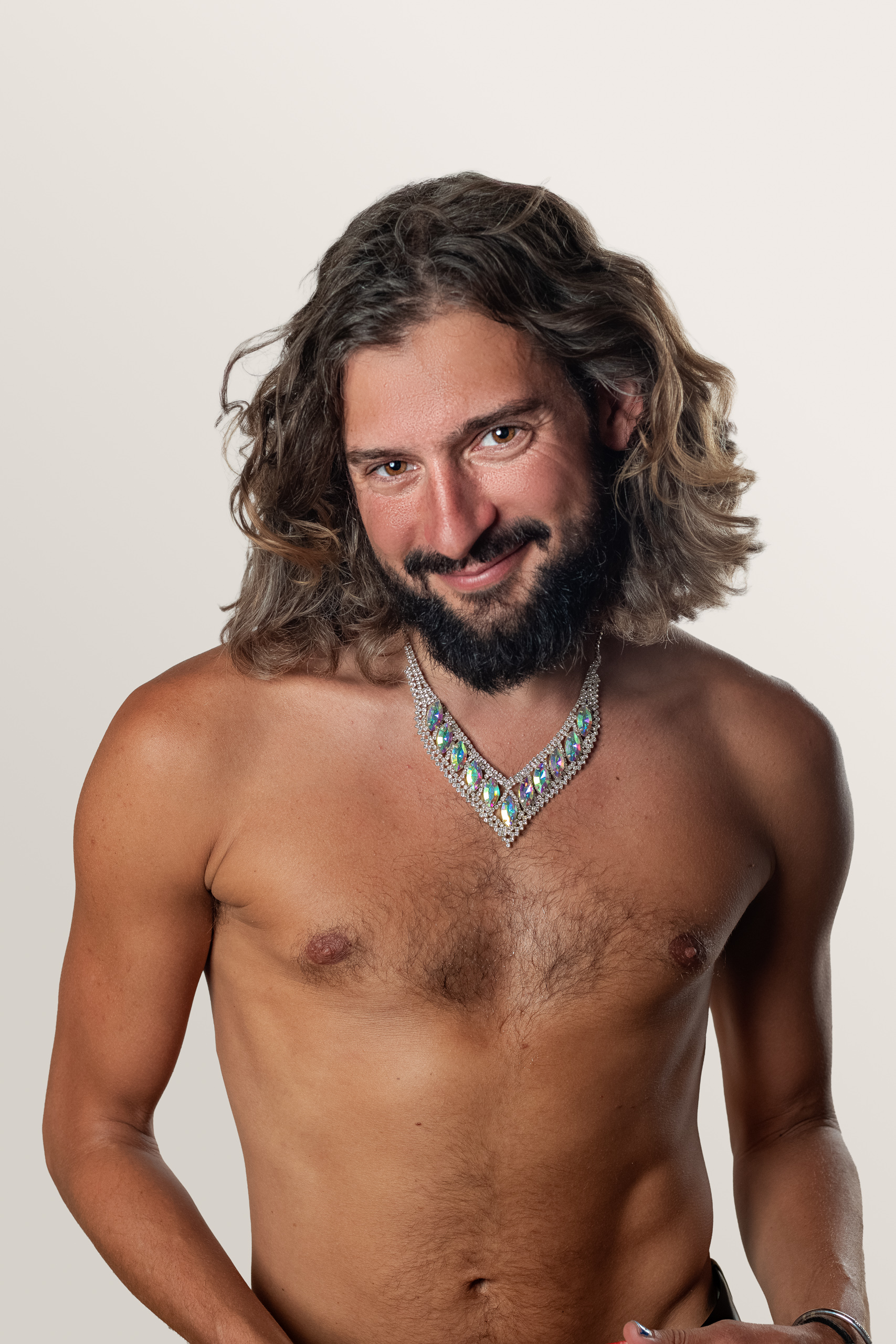 A bare-chested sitter with long wavy hair wears a silver necklace.