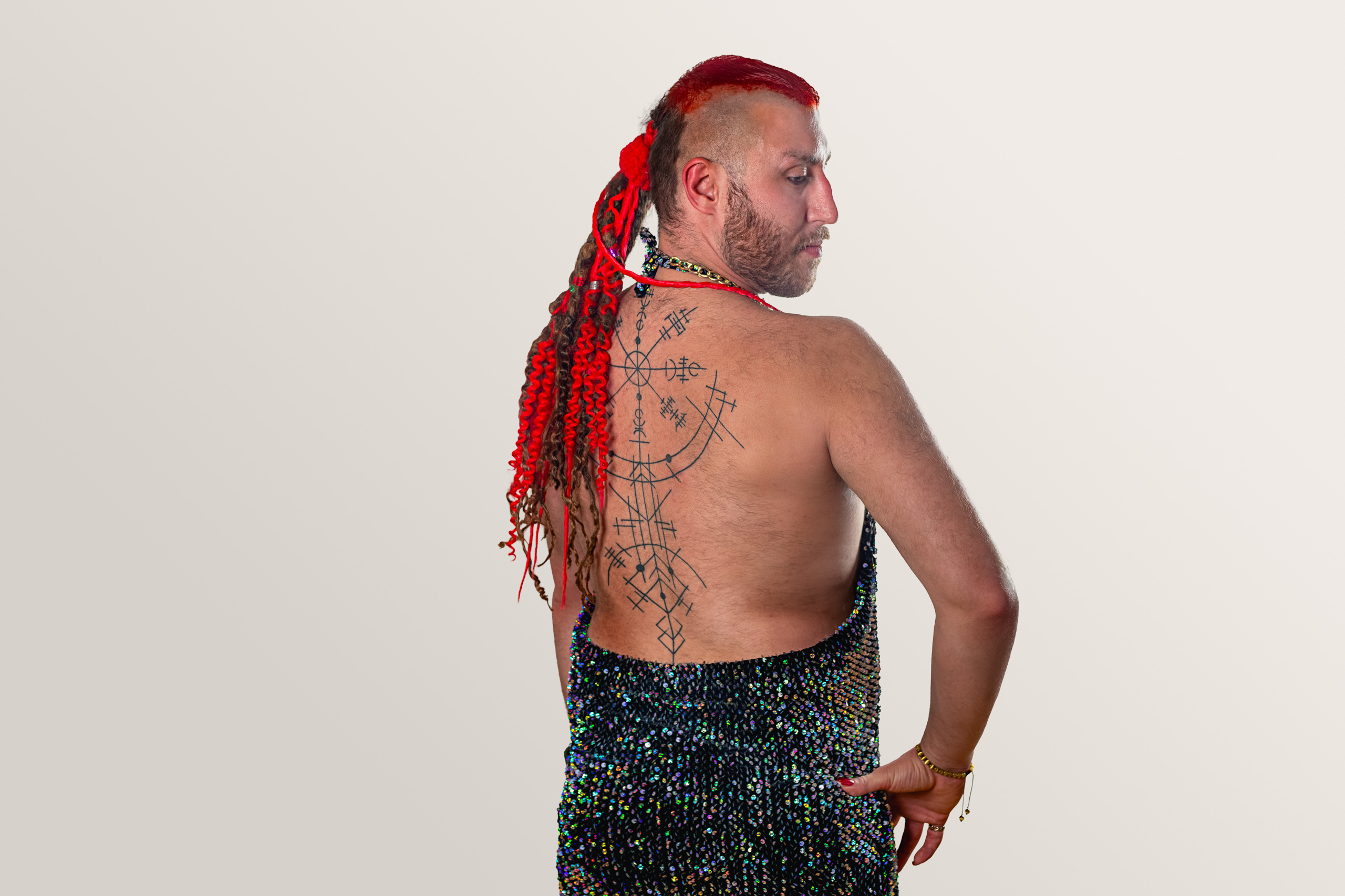 A sitter with long red braids looks over one shoulder, a hand resting on the hip.