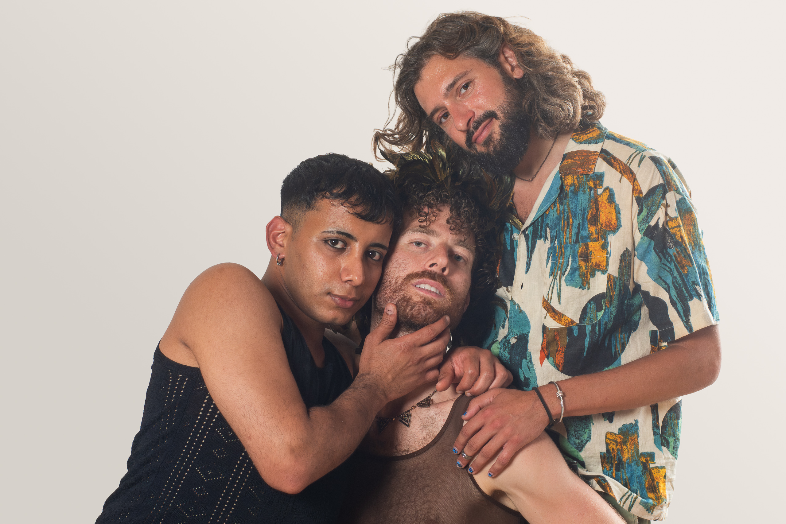 Three people lean together in a tender portrait, with one hand gently cradling a face.