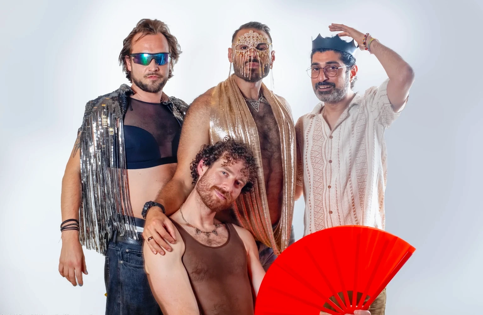 Four costumed figures pose together with gold, silver and a red fan.