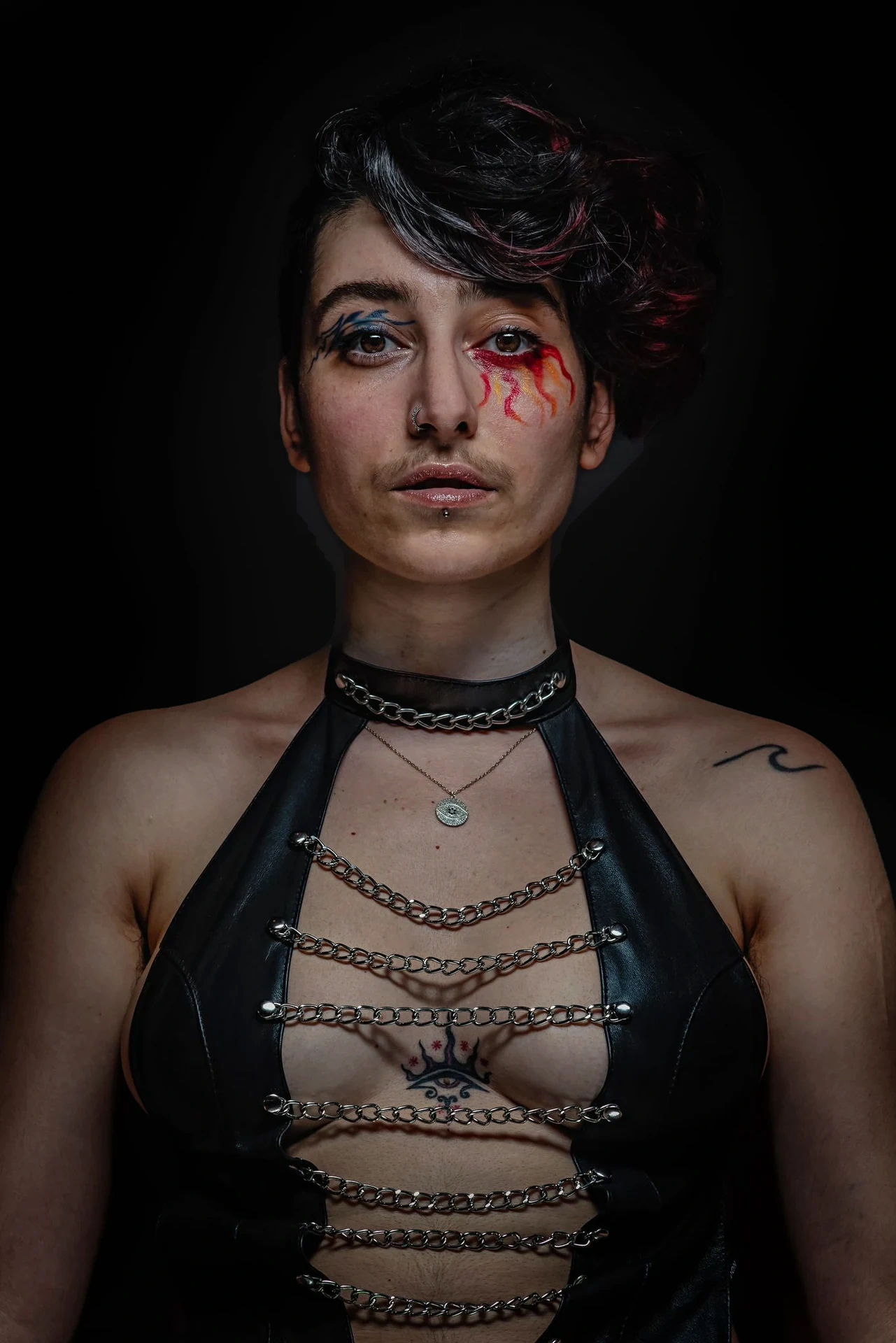 A direct portrait with swept dark hair, eye makeup and black leather.