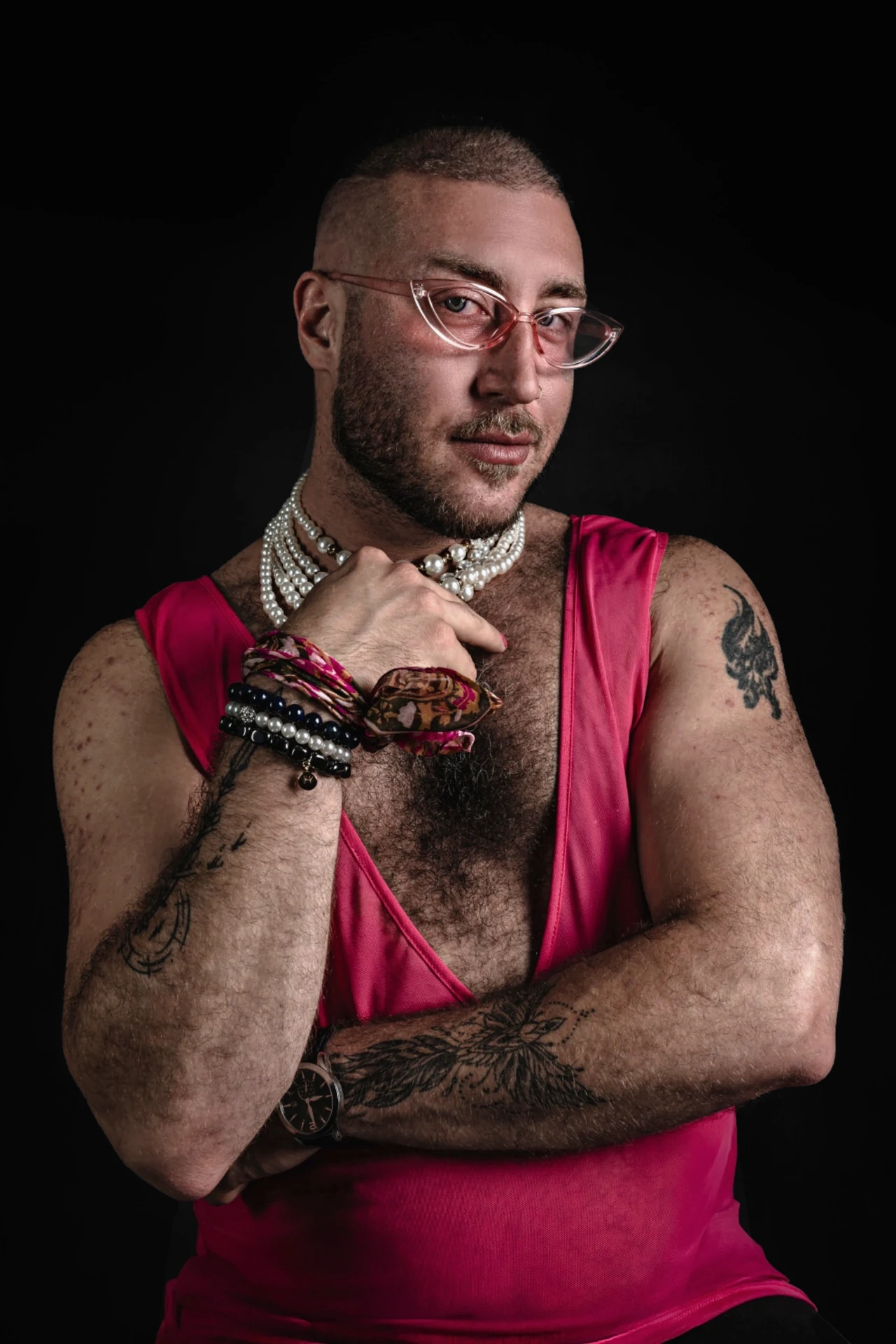 A sitter in pink glasses and a vivid pink sleeveless outfit rests one hand beneath the chin.