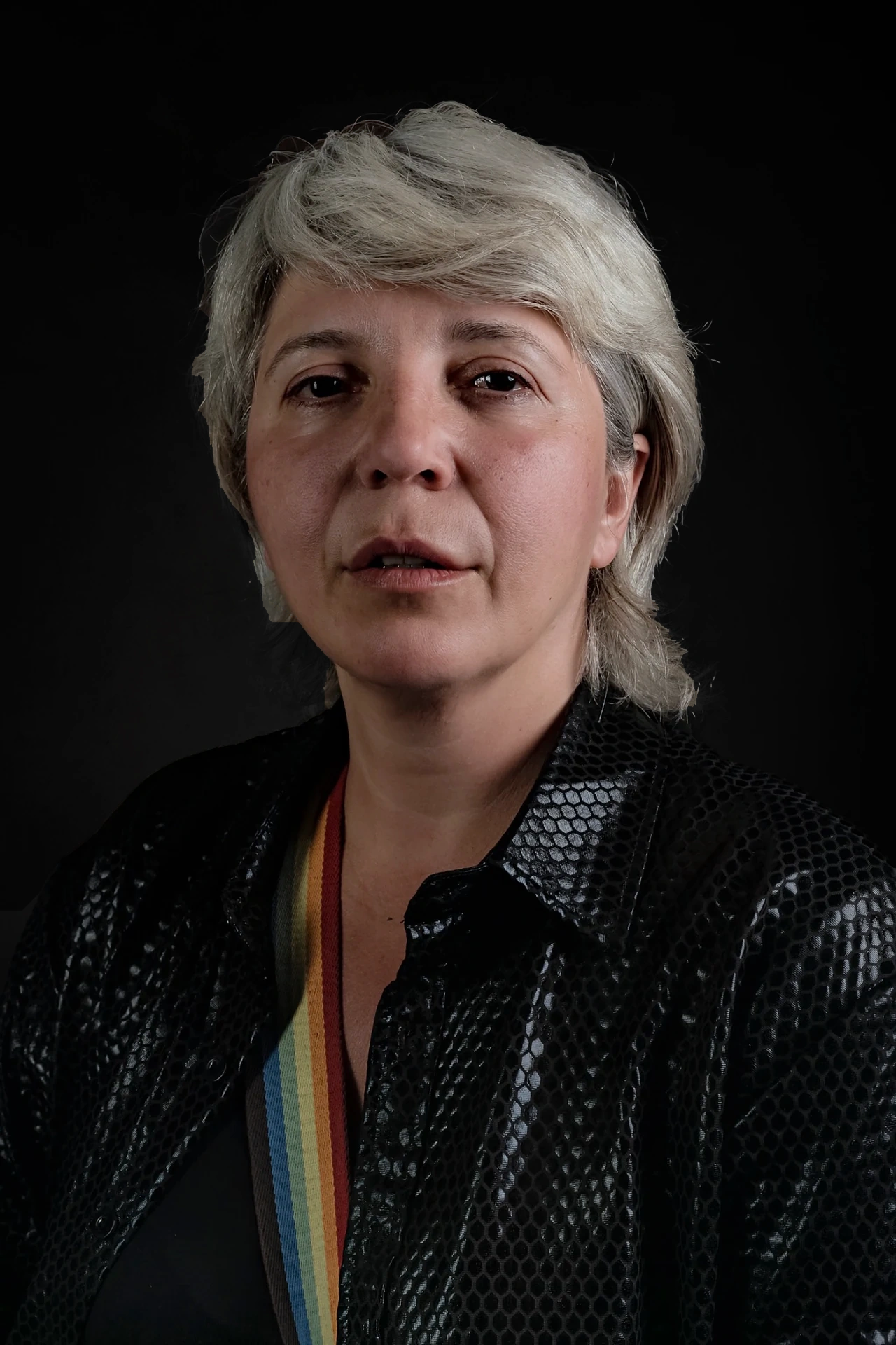 Nata faces the camera in a black textured jacket with a rainbow strap.