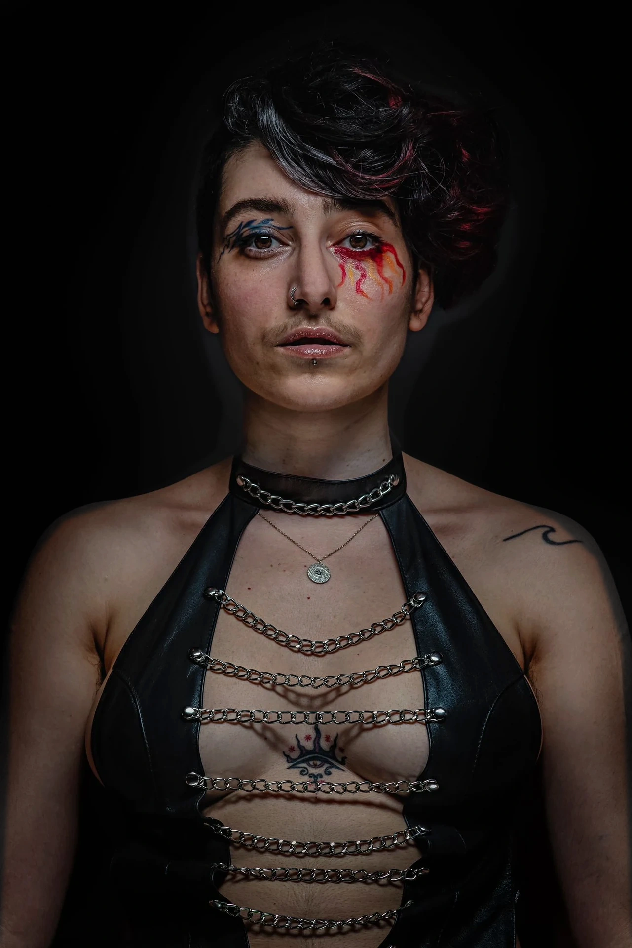 A direct portrait with swept dark hair, eye makeup and black leather.