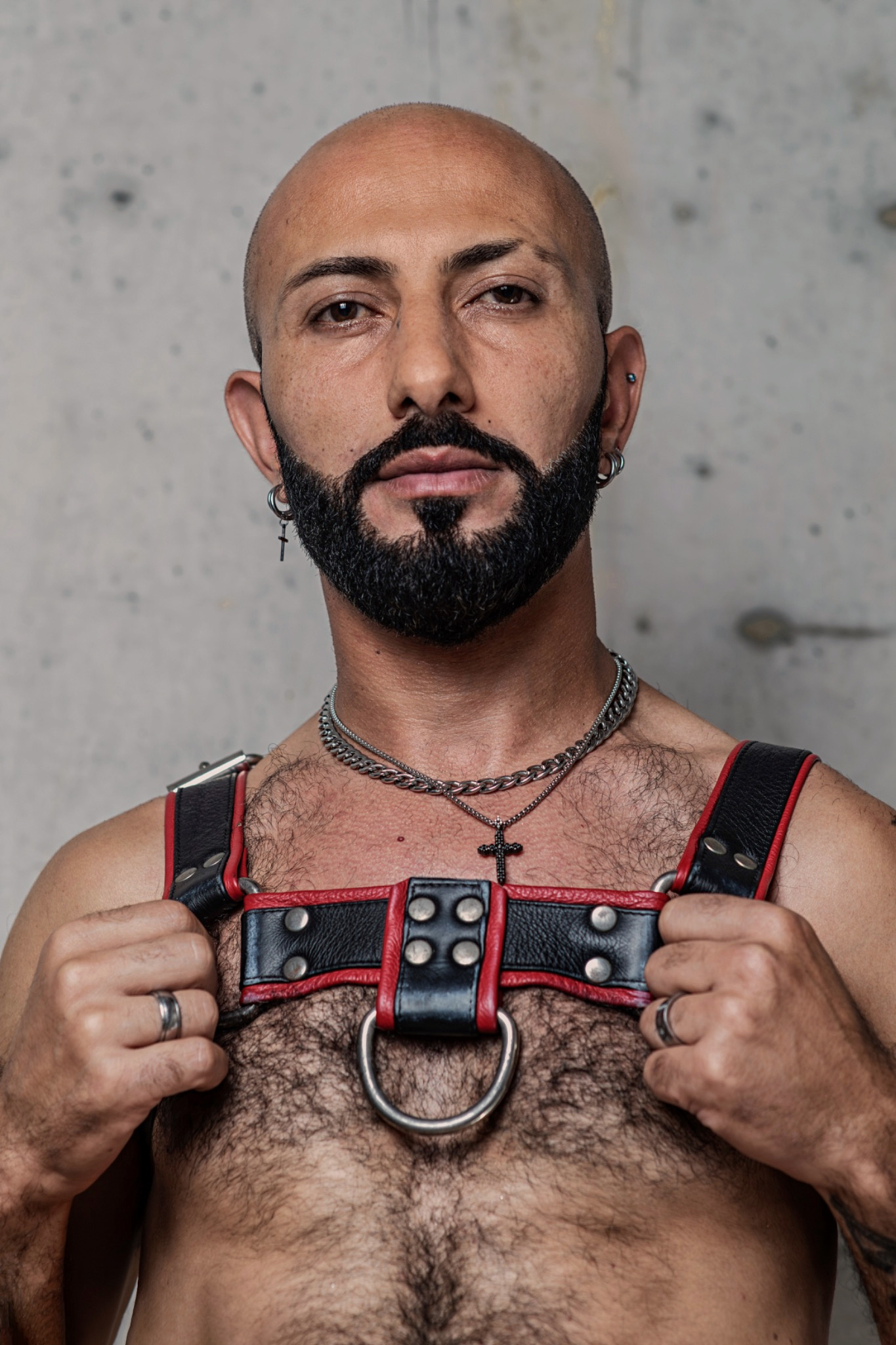 John looks directly at the camera, holding the straps of his harness.