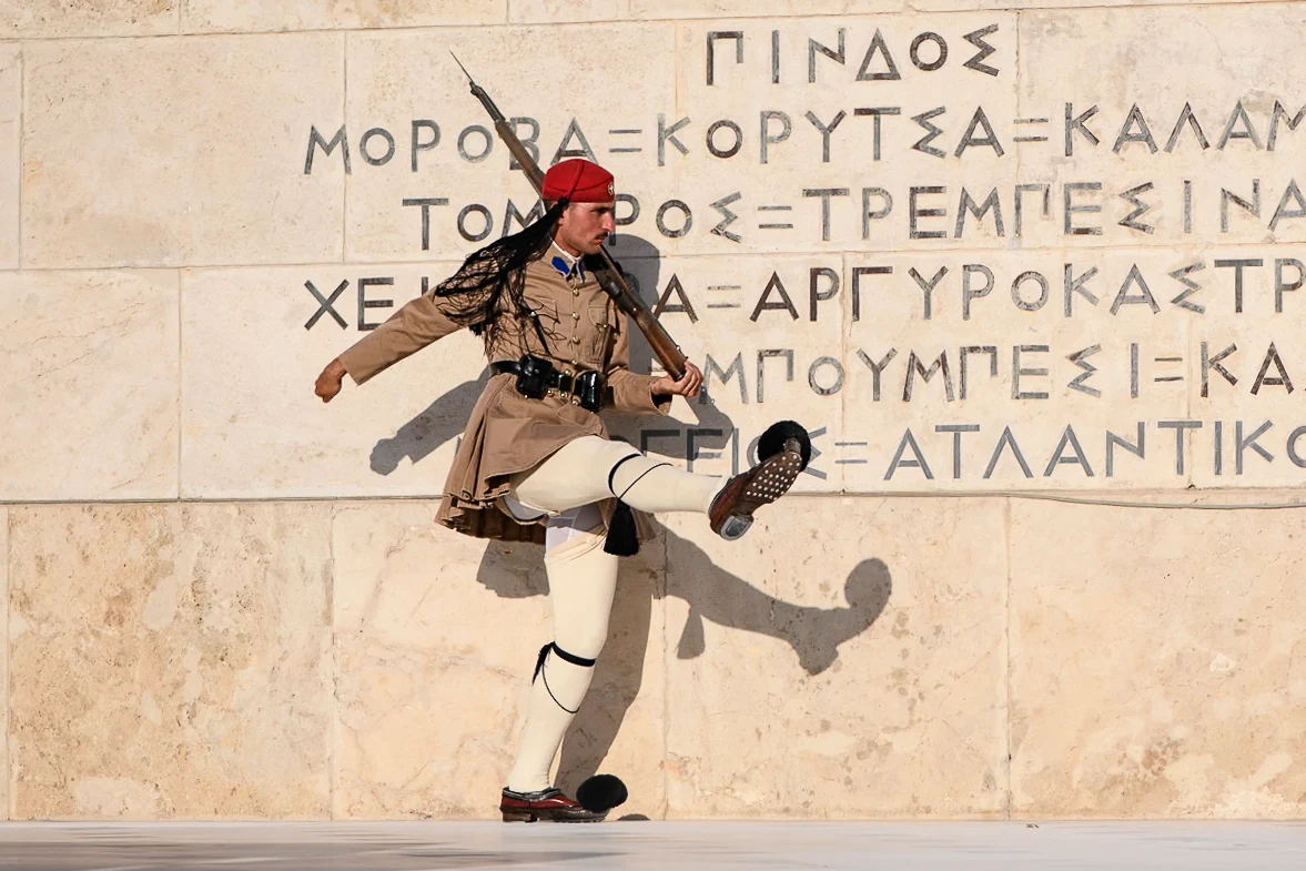 A guard extends one leg and an arm beside a stone inscription, with the shadow repeating his movement.