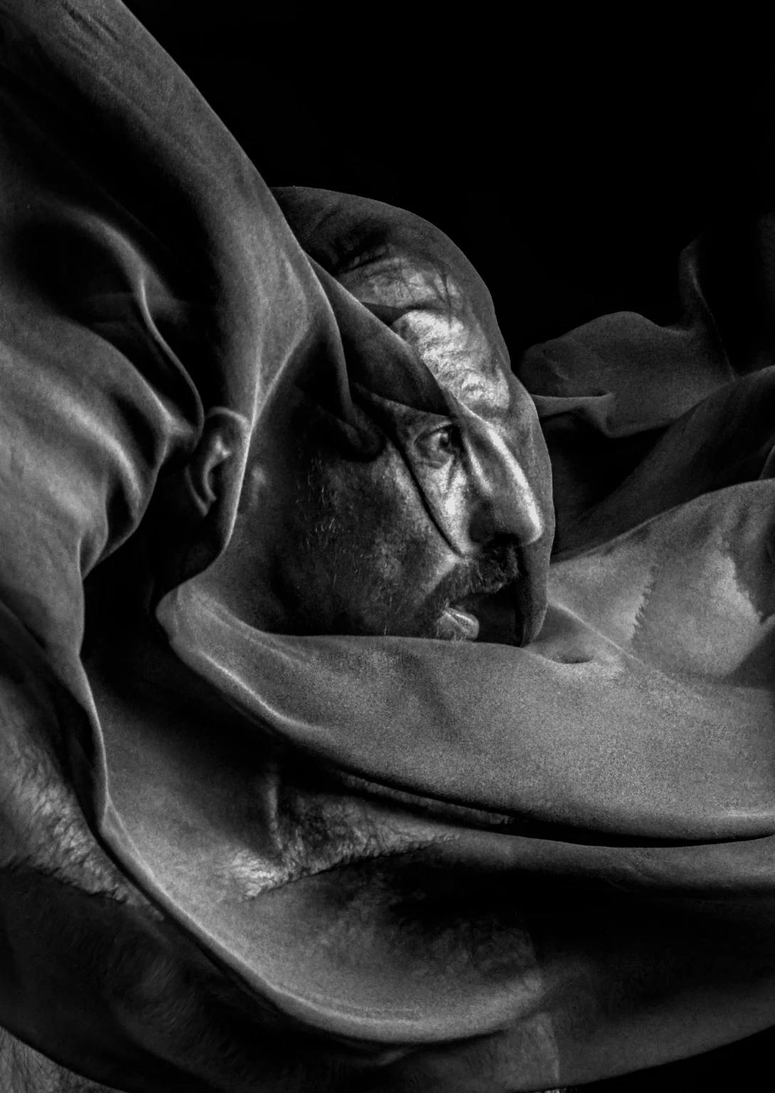 A black-and-white portrait framed by folds of fabric.
