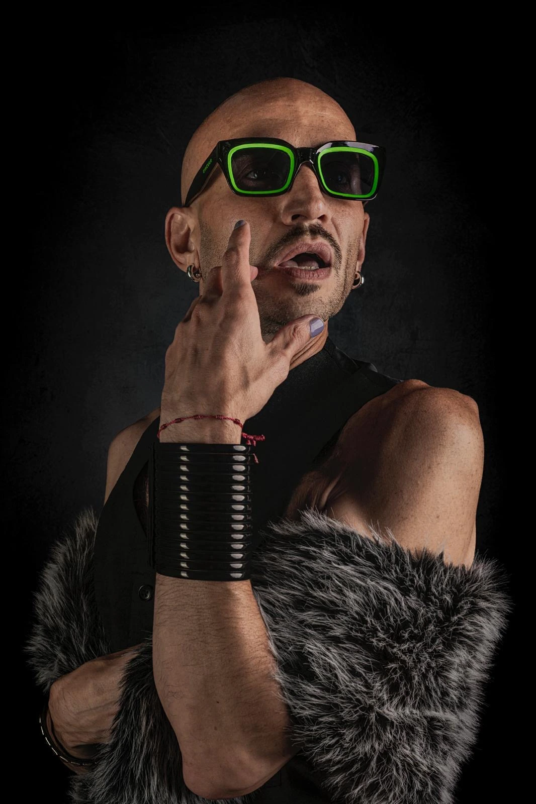 A sitter in green-rimmed sunglasses and fur holds a purple-painted fingertip near the face.