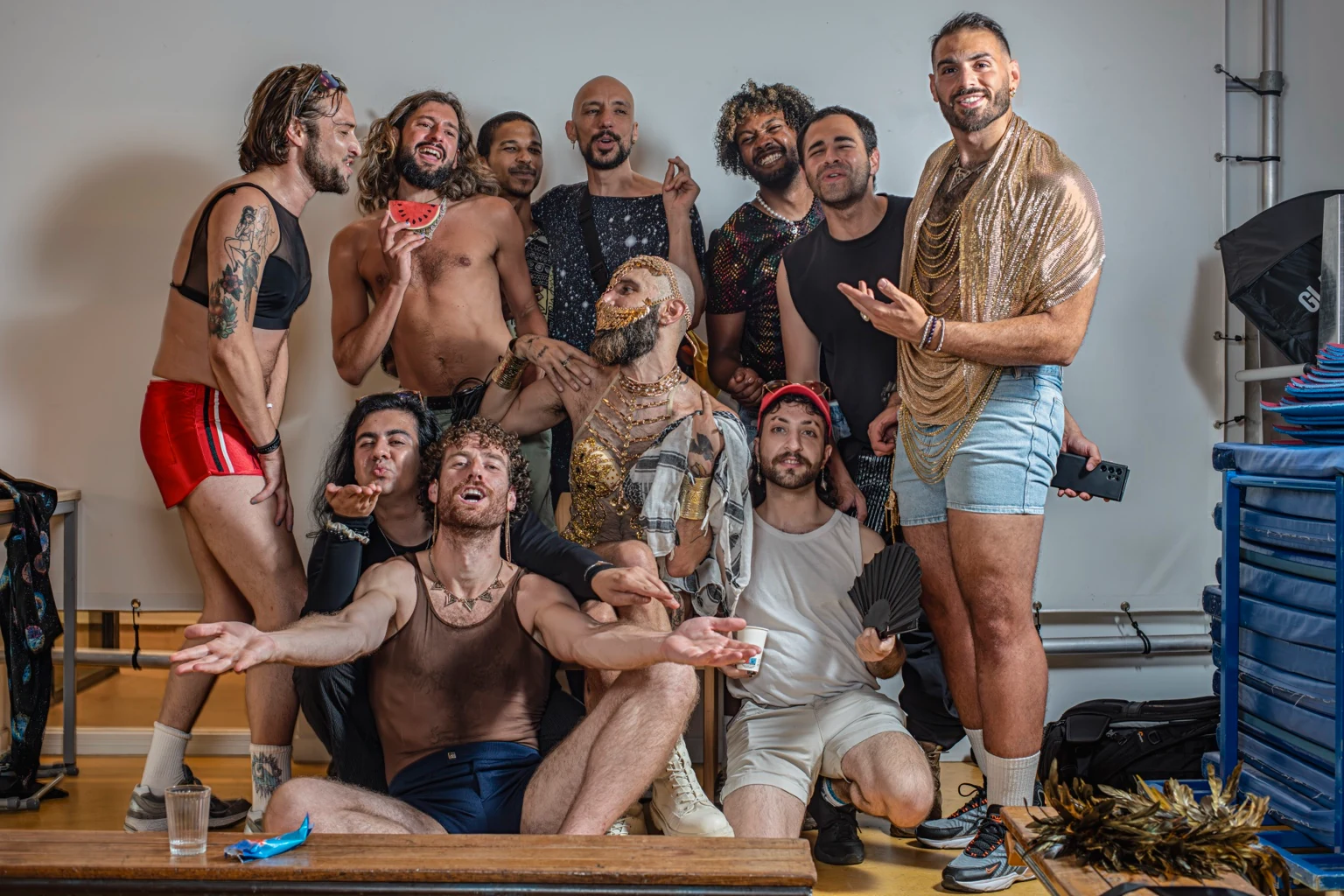 Een groep poseert samen tussen studiobanken, kostuums en attributen.