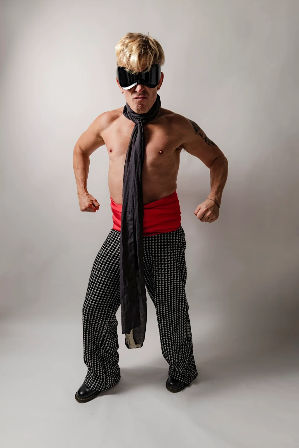 Self-portrait wearing goggles, with fists clenched beside the body.